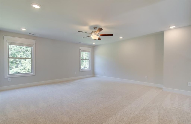 empty room with light carpet, ceiling fan, and a wealth of natural light