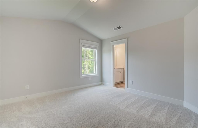 carpeted spare room with vaulted ceiling