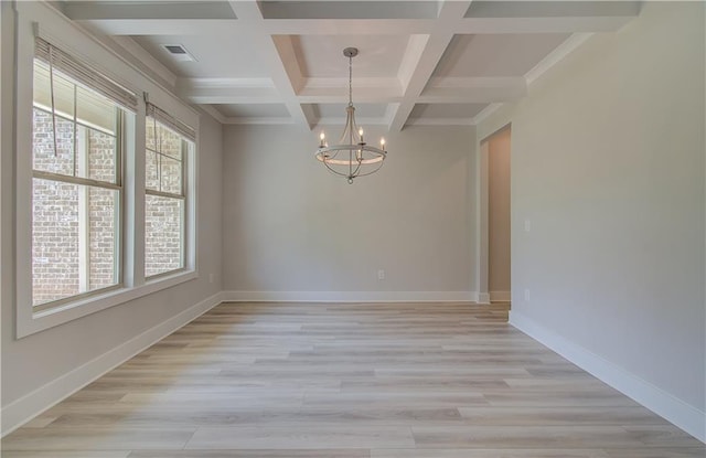 empty room featuring beamed ceiling, coffered ceiling, light wood-type flooring, and an inviting chandelier