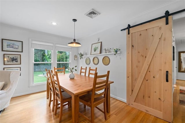 dining room with a barn door, light wood-style floors, crown molding, baseboards, and recessed lighting