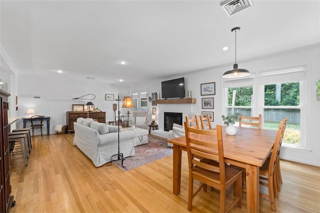 living area with a fireplace, light wood-style flooring, recessed lighting, and crown molding