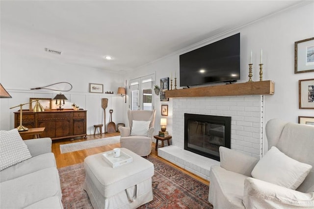 living area with wood finished floors, a fireplace, crown molding, and recessed lighting