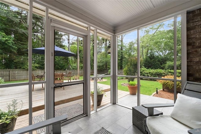 unfurnished sunroom featuring healthy amount of natural light, outdoor dining space, and view of scattered trees