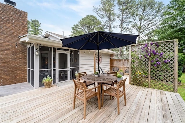 deck with outdoor dining area, a sunroom, and fence