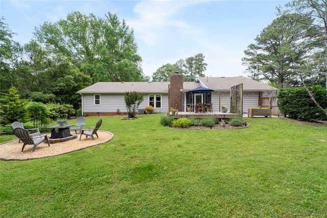 rear view of property featuring an outdoor fire pit, a sunroom, a chimney, and a lawn