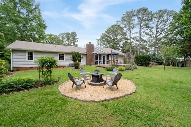 rear view of house featuring an outdoor fire pit, a sunroom, a chimney, a yard, and crawl space