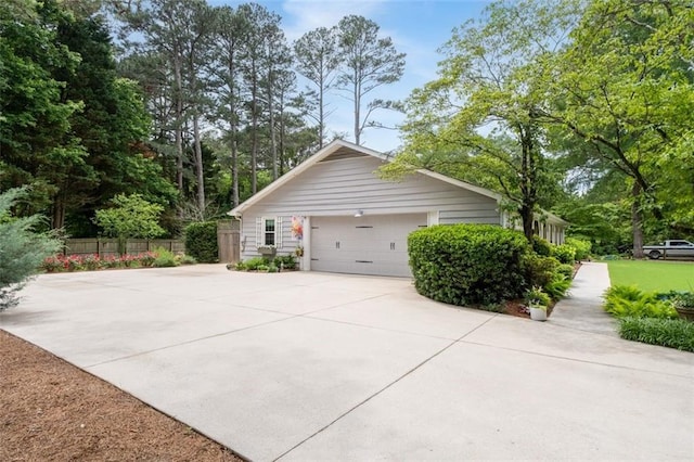 view of home's exterior featuring concrete driveway, fence, and an attached garage