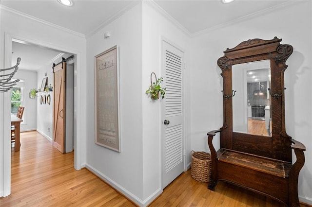 hall with light wood finished floors, crown molding, recessed lighting, baseboards, and a barn door