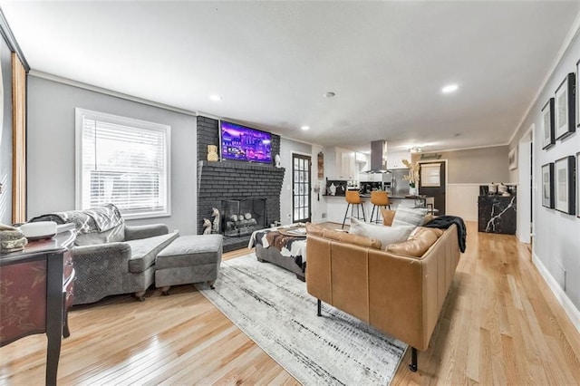 living room featuring a brick fireplace, crown molding, and light hardwood / wood-style flooring