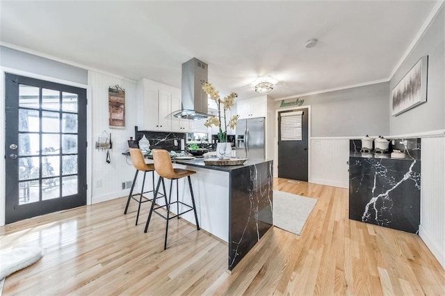 kitchen featuring white cabinets, stainless steel fridge, island exhaust hood, and light hardwood / wood-style floors