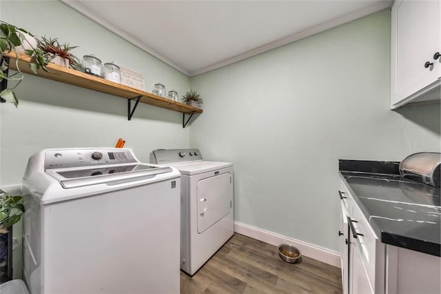 laundry room with dark wood-type flooring, cabinets, washer and dryer, and crown molding