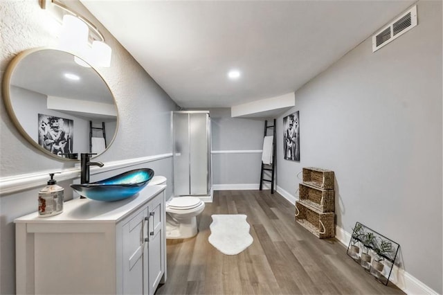 bathroom with a shower with shower door, wood-type flooring, toilet, and vanity