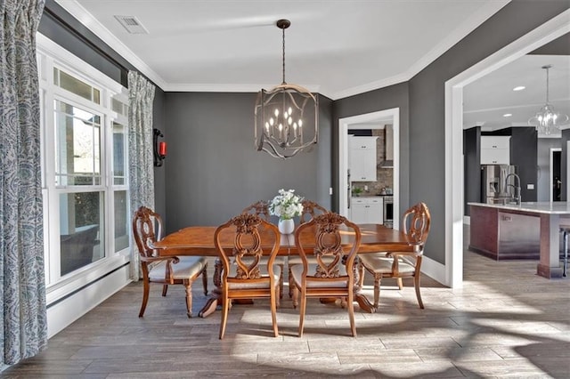 dining room with hardwood / wood-style floors, an inviting chandelier, and ornamental molding