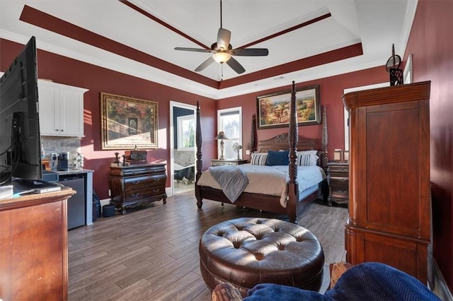 bedroom with a tray ceiling, hardwood / wood-style flooring, crown molding, and refrigerator