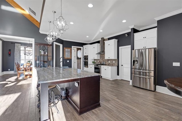 kitchen with white cabinetry, appliances with stainless steel finishes, a chandelier, and a center island