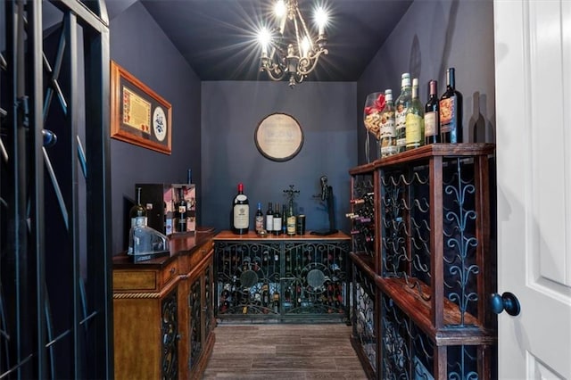 wine room with hardwood / wood-style flooring, a notable chandelier, lofted ceiling, and bar