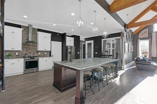 kitchen with sink, gas stove, decorative light fixtures, wall chimney range hood, and a large island