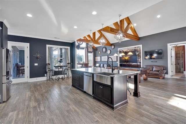 kitchen featuring a breakfast bar area, stainless steel appliances, decorative light fixtures, sink, and a kitchen island with sink