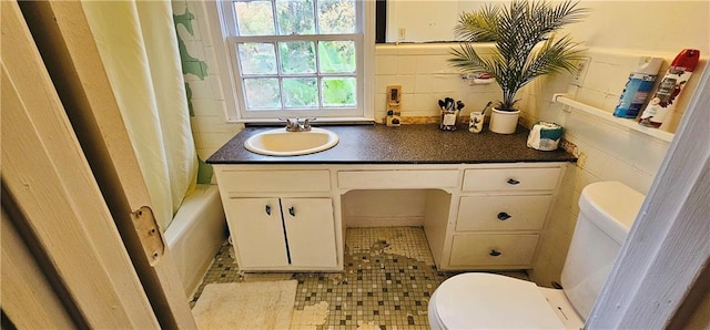 full bathroom with toilet, vanity, tile patterned floors, and tile walls