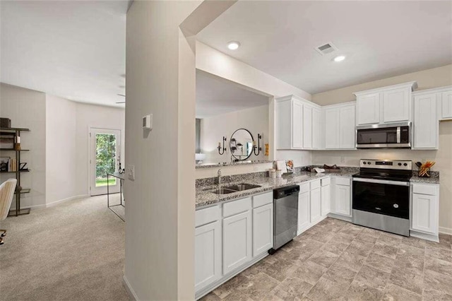 kitchen with light stone counters, stainless steel appliances, sink, and white cabinets