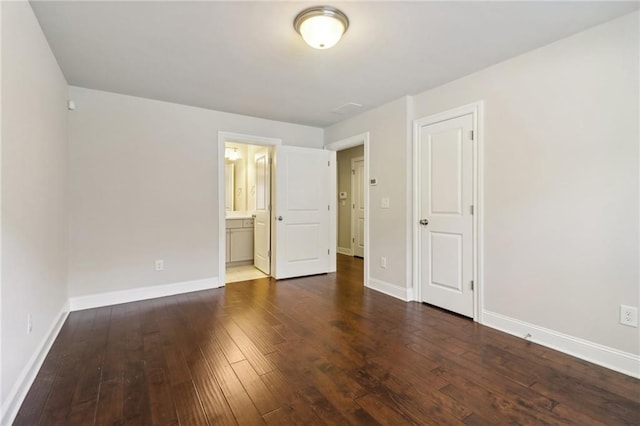 unfurnished bedroom featuring connected bathroom, a closet, and dark hardwood / wood-style flooring