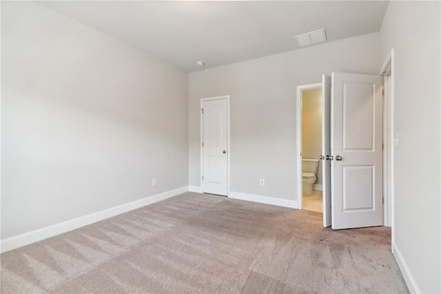 unfurnished bedroom featuring ensuite bath and light colored carpet