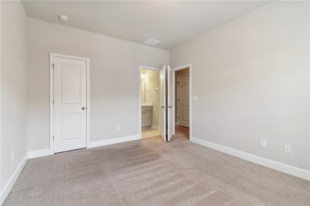 unfurnished bedroom featuring connected bathroom and light carpet