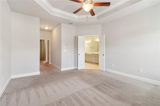 carpeted spare room featuring ceiling fan and a raised ceiling