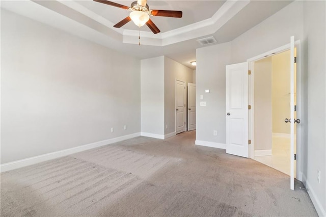 unfurnished bedroom with ceiling fan, light colored carpet, and a raised ceiling