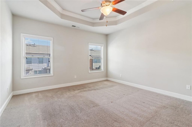 carpeted empty room featuring a raised ceiling and ceiling fan