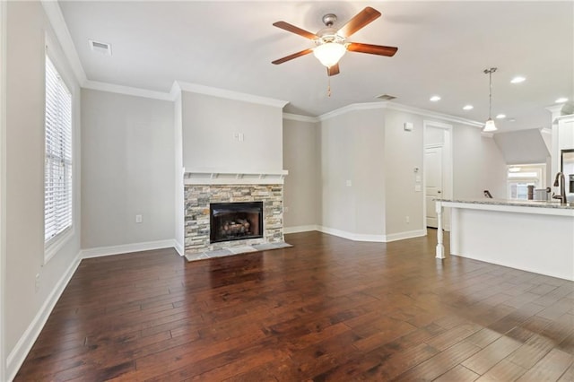 unfurnished living room featuring sink, a fireplace, ceiling fan, crown molding, and dark hardwood / wood-style floors