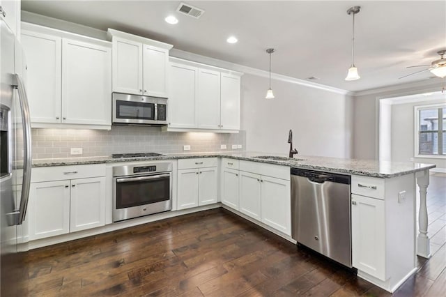 kitchen featuring appliances with stainless steel finishes, sink, dark hardwood / wood-style flooring, white cabinetry, and pendant lighting