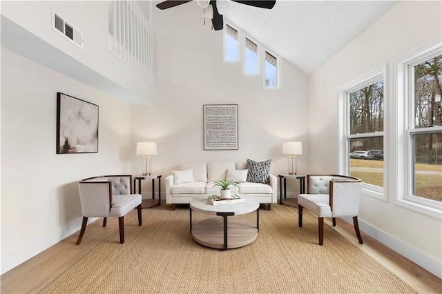 living room featuring ceiling fan, light hardwood / wood-style flooring, high vaulted ceiling, and plenty of natural light