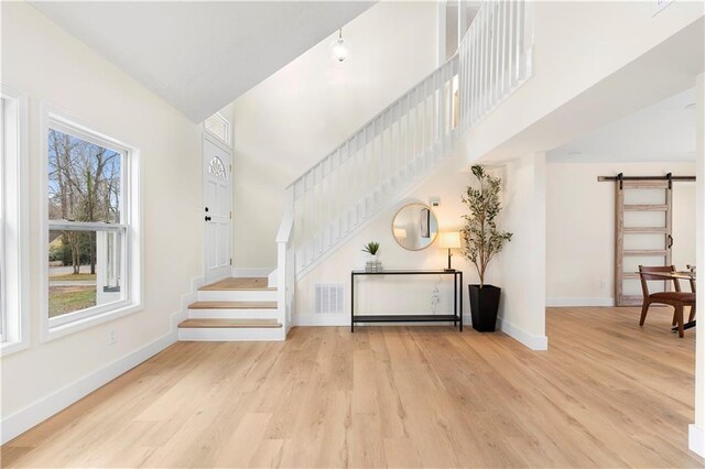 foyer featuring a healthy amount of sunlight, light hardwood / wood-style flooring, and a barn door