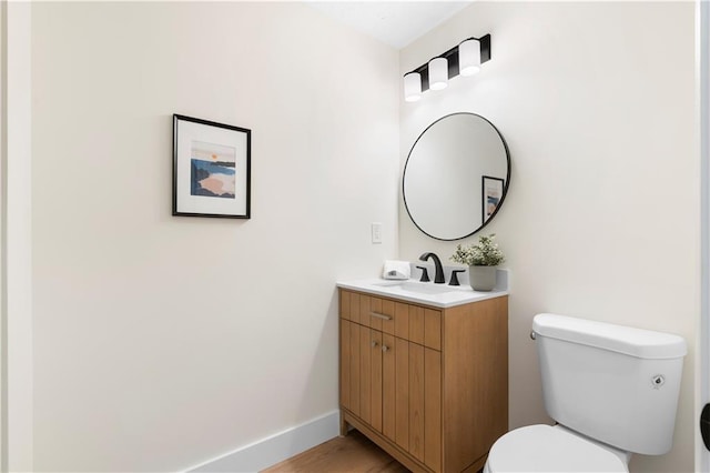 bathroom with toilet, vanity, and hardwood / wood-style floors