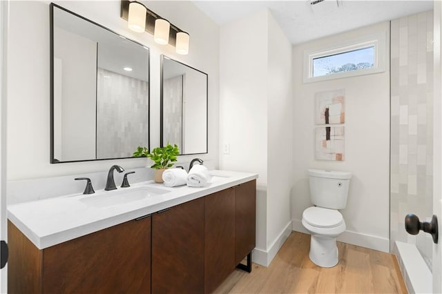 bathroom featuring walk in shower, hardwood / wood-style flooring, vanity, and toilet