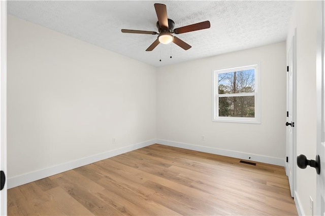 empty room featuring ceiling fan, light wood-type flooring, and a textured ceiling