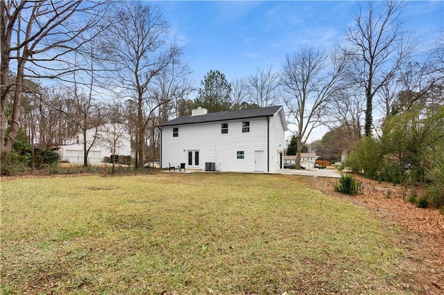 rear view of house with central AC and a lawn