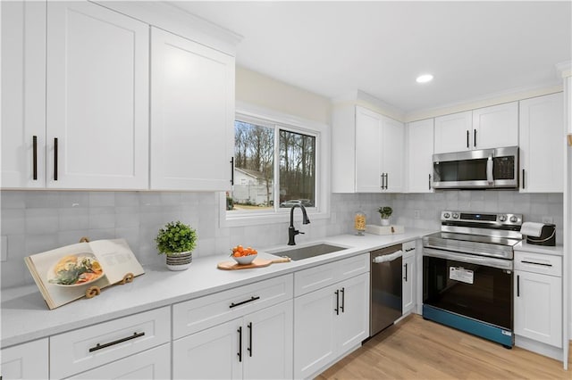 kitchen featuring white cabinets, appliances with stainless steel finishes, tasteful backsplash, and sink