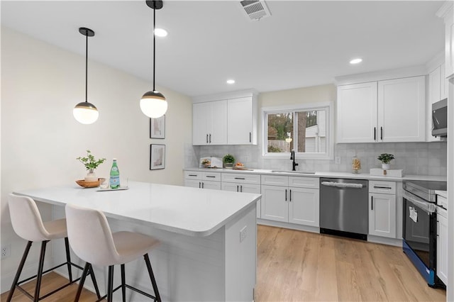 kitchen with tasteful backsplash, appliances with stainless steel finishes, pendant lighting, white cabinets, and sink