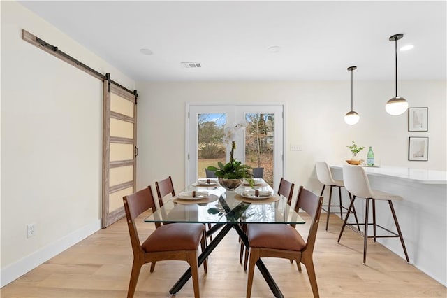 dining space featuring light wood-type flooring and a barn door