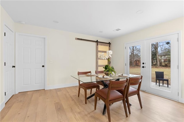 dining room with light hardwood / wood-style floors and a barn door