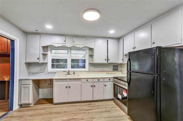 kitchen with a sink, stainless steel electric range oven, open shelves, and freestanding refrigerator