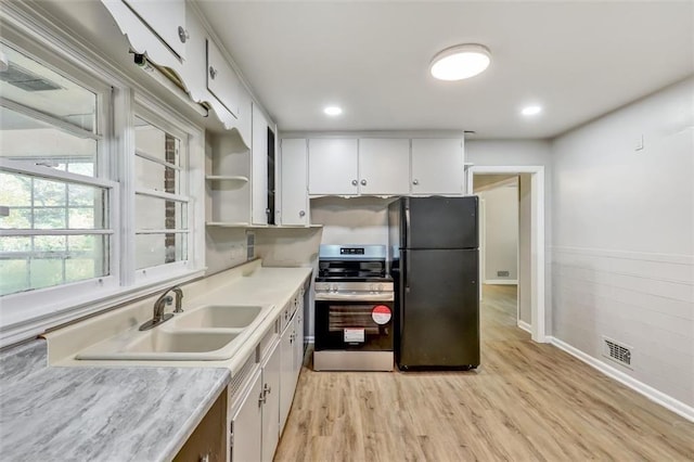 kitchen featuring white cabinets, stainless steel range with electric cooktop, light countertops, freestanding refrigerator, and light wood finished floors