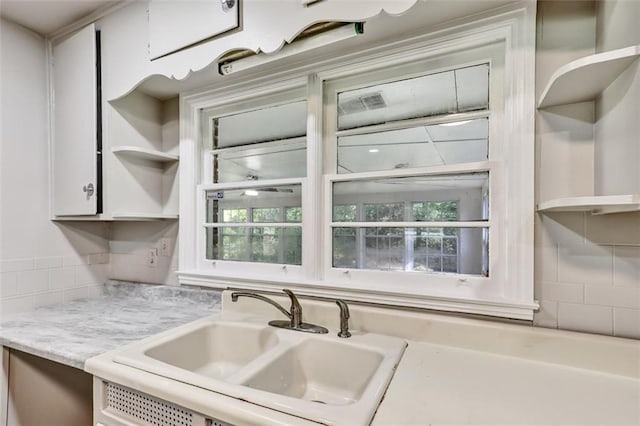 kitchen featuring light stone countertops, decorative backsplash, open shelves, a sink, and white cabinetry