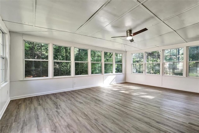 unfurnished sunroom with wood finished floors, a wooden deck, and baseboards