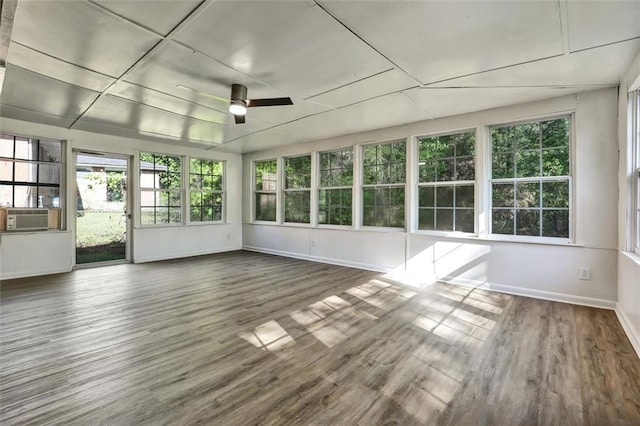 unfurnished sunroom with a wooden deck, a healthy amount of sunlight, wood finished floors, and baseboards