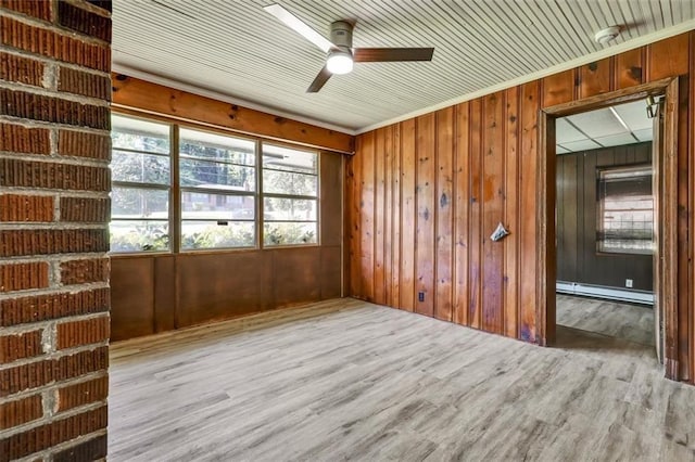 unfurnished room with a baseboard heating unit, ceiling fan, wood walls, and wood finished floors