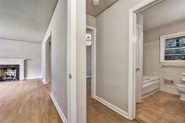 hall featuring light wood-style flooring and tile walls