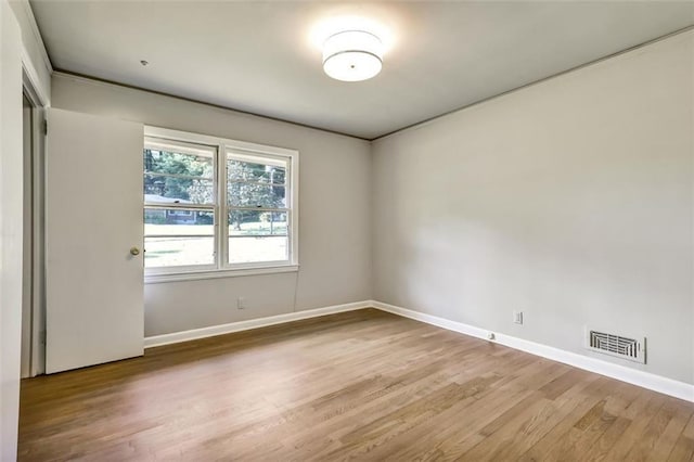 spare room with wood finished floors, visible vents, and baseboards